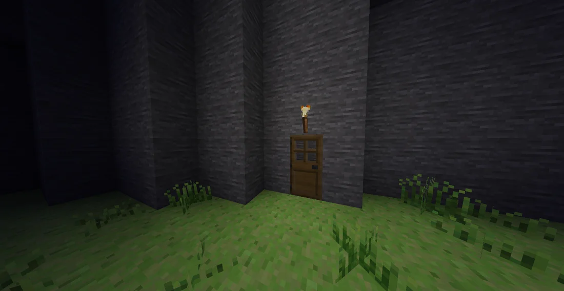 A cozy cave, viewed from the outside of the front door with a torch at night